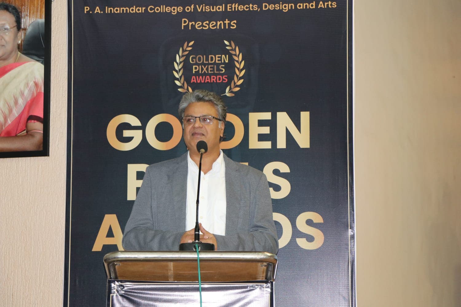 Speaker at the podium in front of the Golden Pixels Awards banner