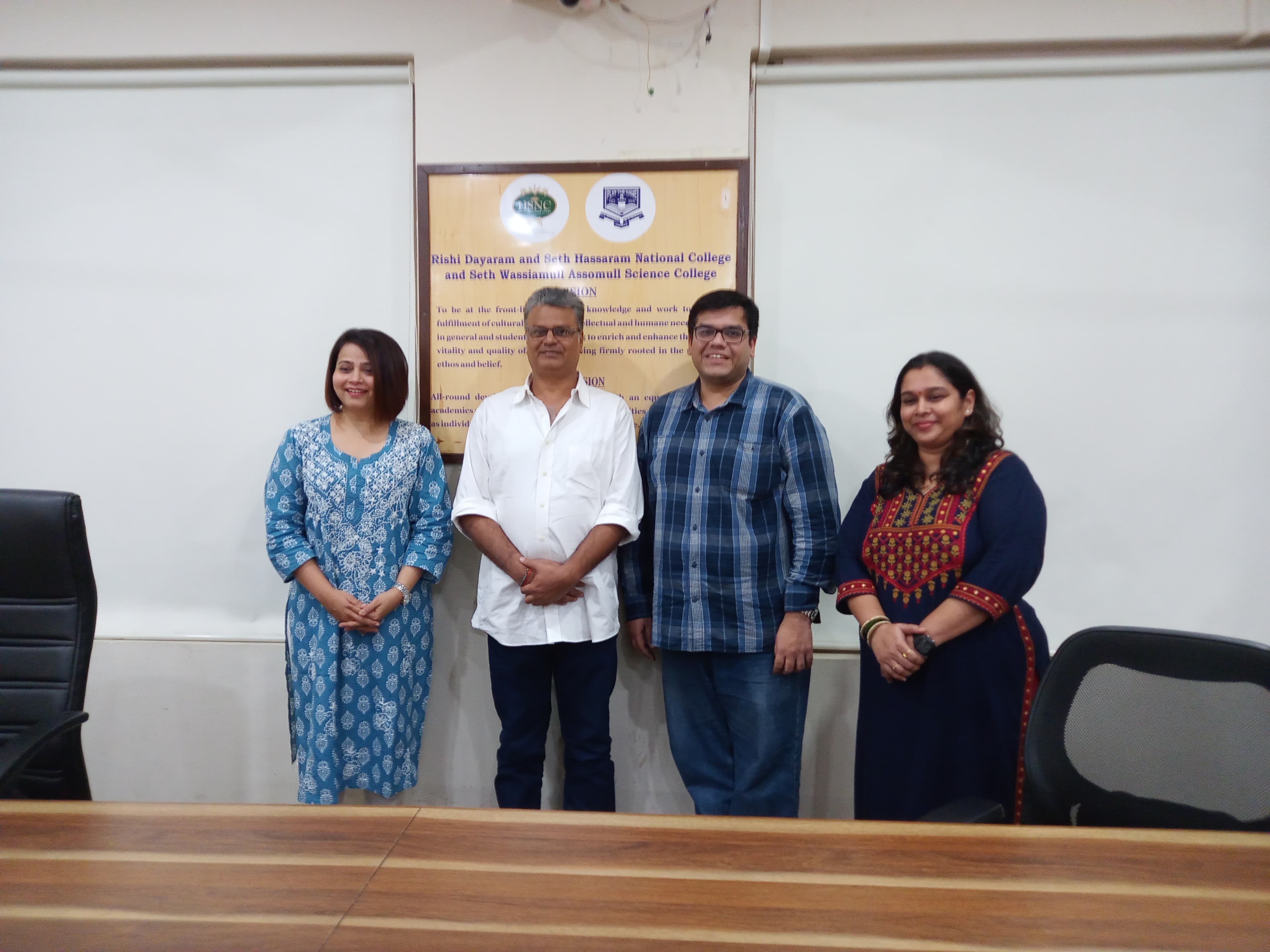 Four people standing together in a college conference room