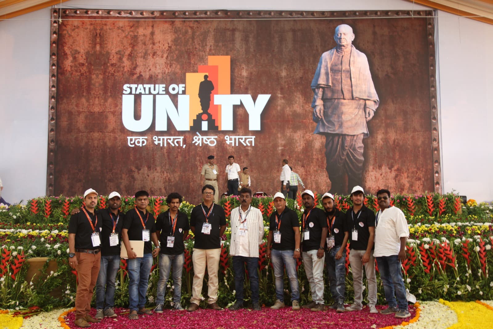 Production crew posing on the flower-decked Statue of Unity event stage